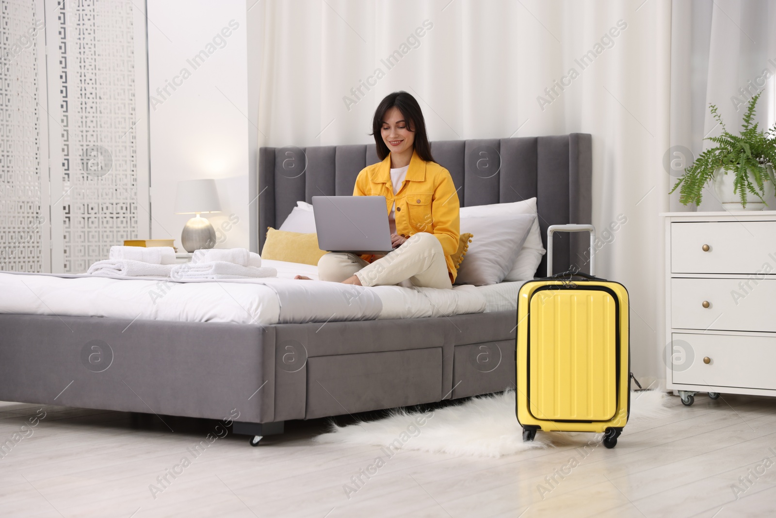 Photo of Woman with laptop on bed in her hotel room