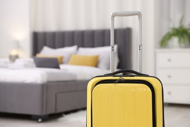 Photo of Suitcase and laptop on bed in hotel room, selective focus