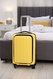 Photo of Stylish suitcase near bed in hotel room