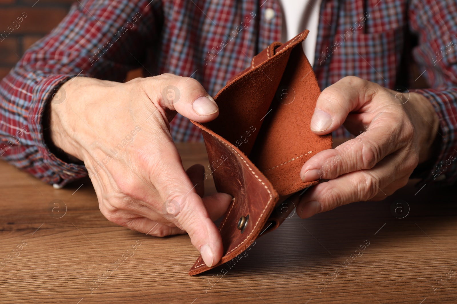 Photo of Senior man with empty wallet at wooden table, closeup. Financial problems