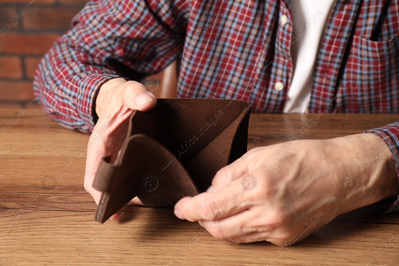 Photo of Senior man with empty wallet at wooden table, closeup. Financial problems