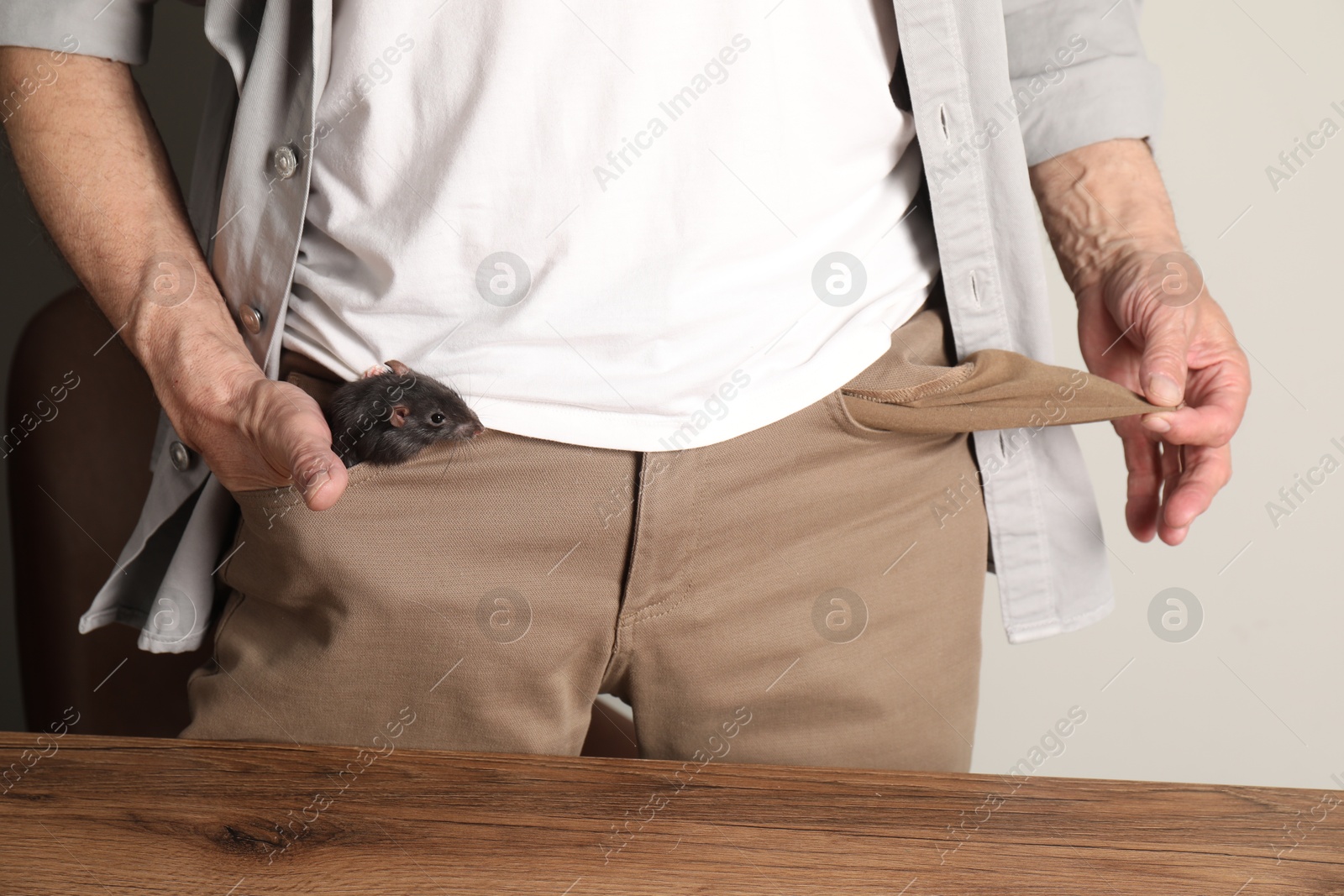 Photo of Senior man with rat in his pock near wooden table, closeup. Financial problems