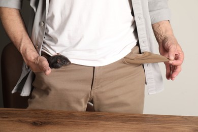 Photo of Senior man with rat in his pock near wooden table, closeup. Financial problems