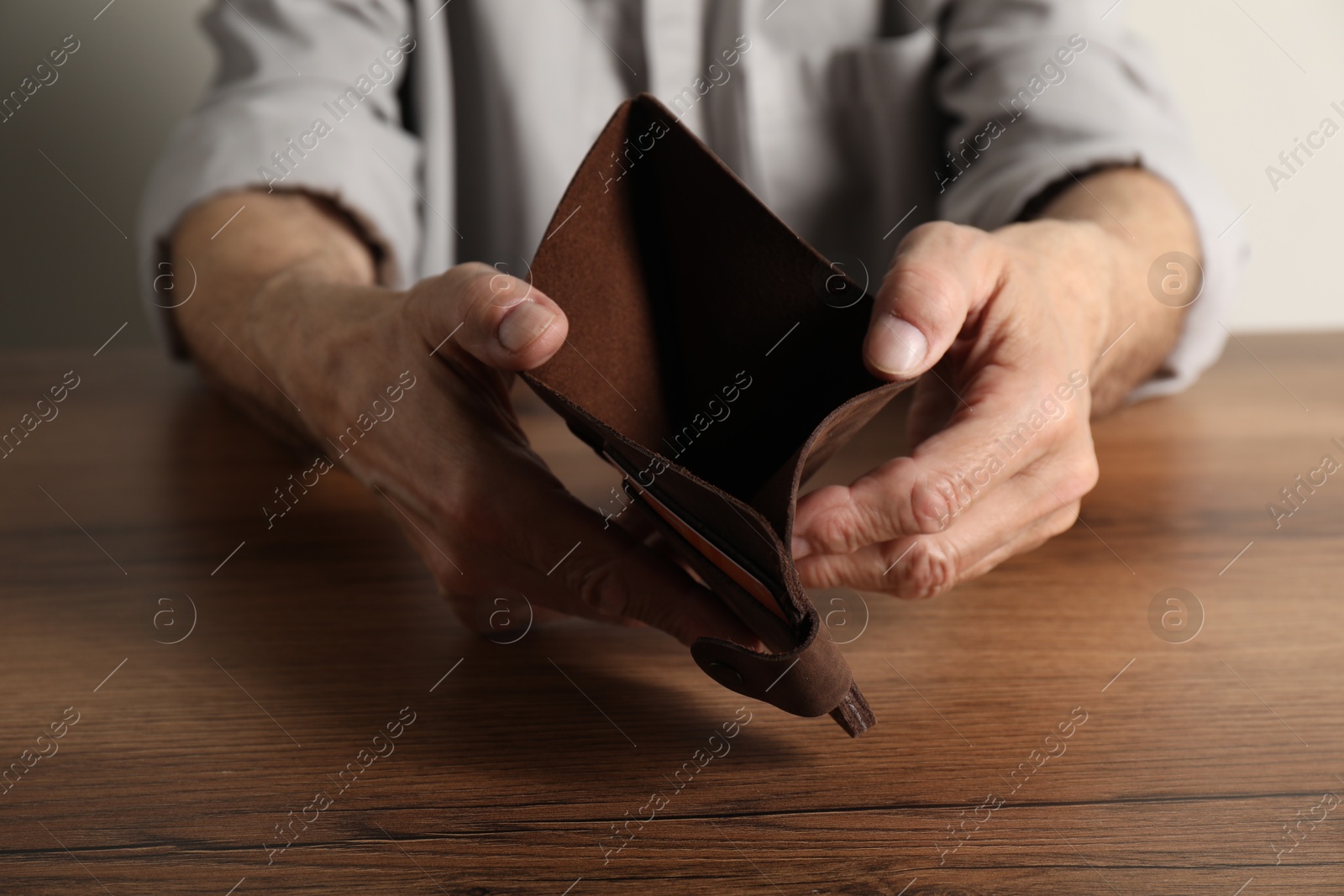 Photo of Senior man with empty wallet at wooden table, closeup. Financial problems