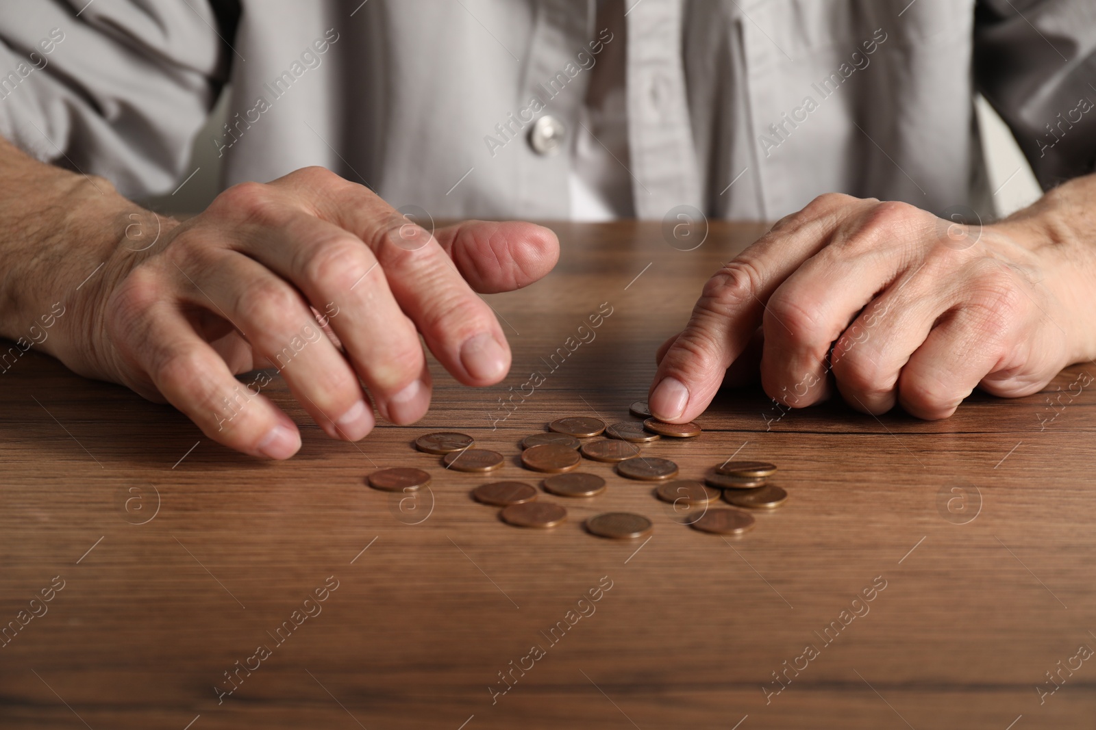 Photo of Senior man counting coins at wooden table, closeup. Financial problems