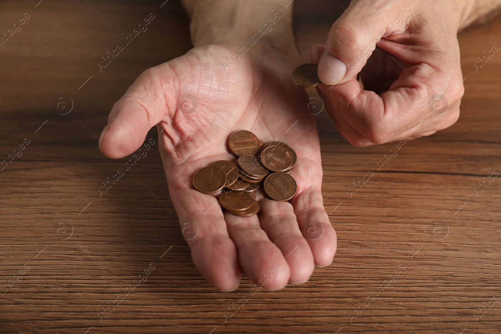 Photo of Senior man counting coins at wooden table, closeup. Financial problems