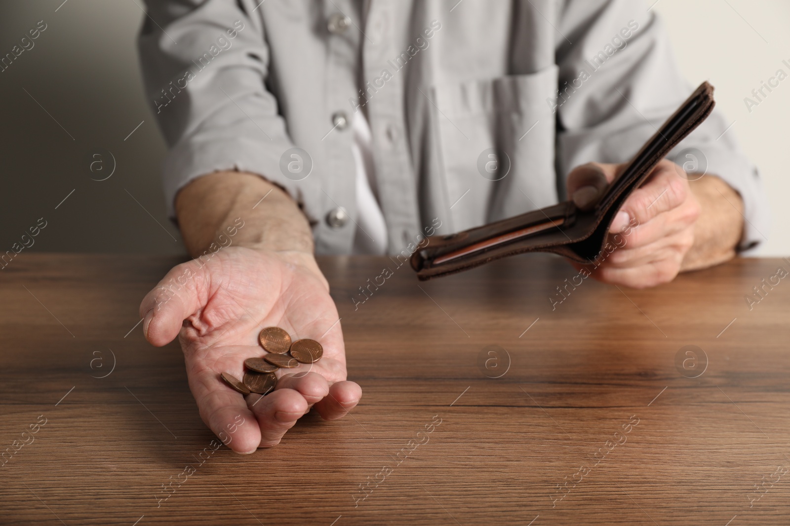 Photo of Senior man with coins and wallet at wooden table, closeup. Financial problems