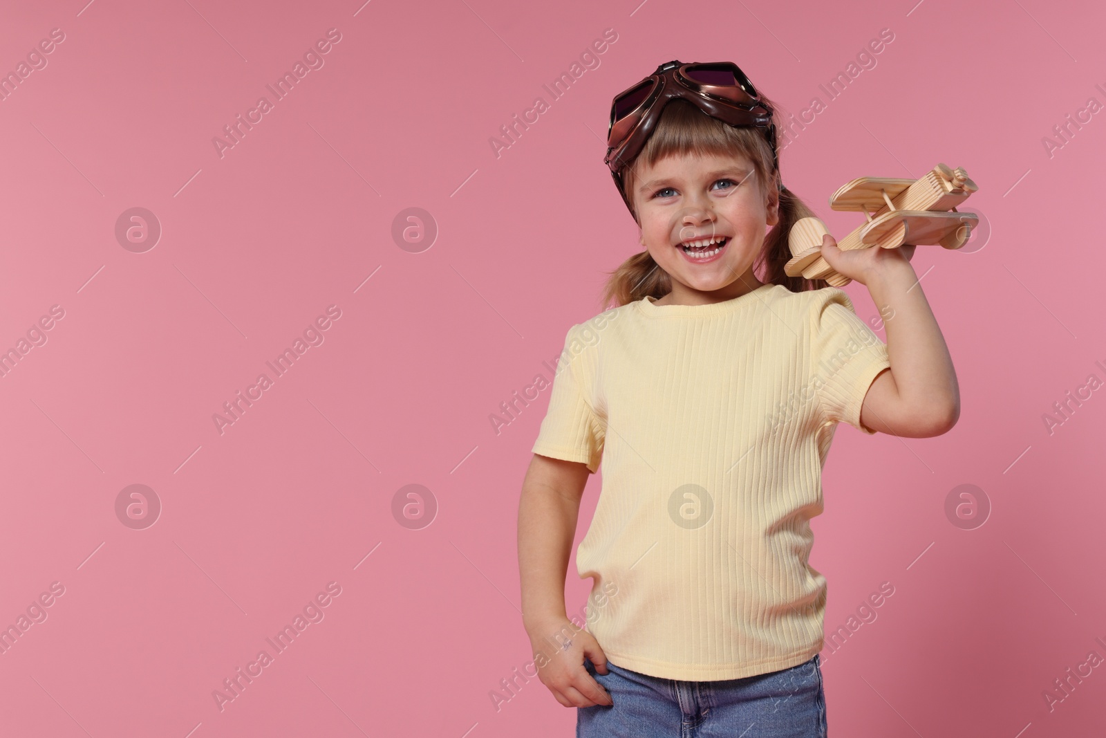 Photo of Happy little girl with toy plane on pink background. Space for text