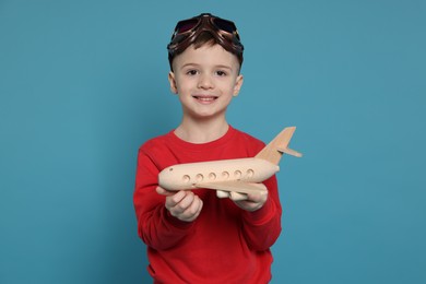 Photo of Happy little boy with toy plane on light blue background