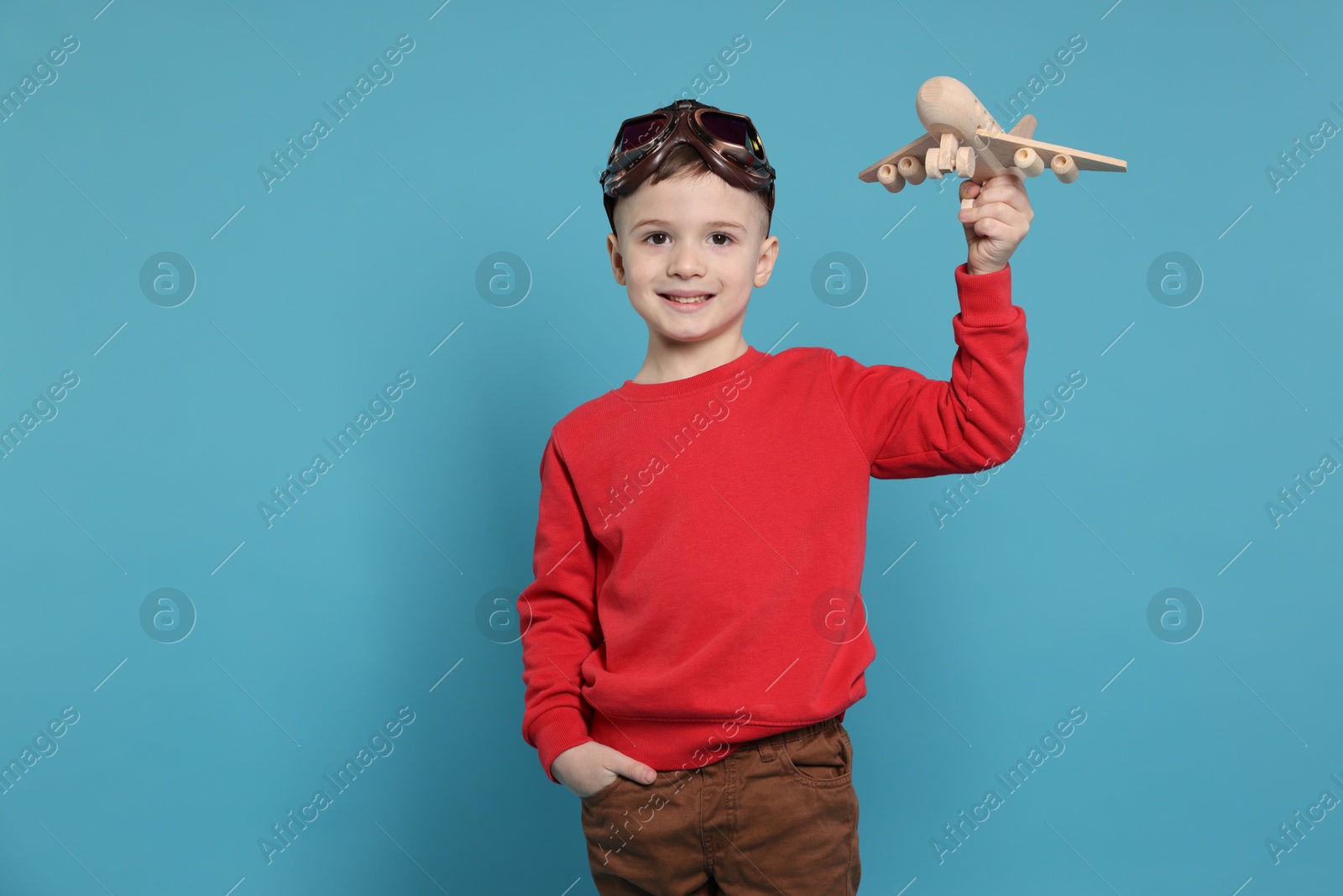 Photo of Happy little boy with toy plane on light blue background. Space for text