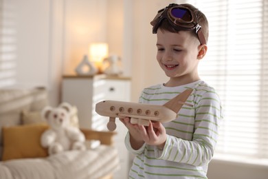 Photo of Happy little boy with toy plane at home. Space for text