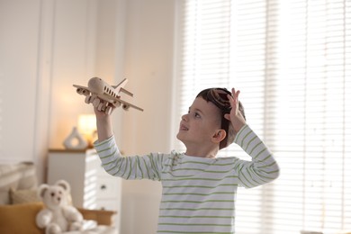 Happy little boy playing with toy plane at home