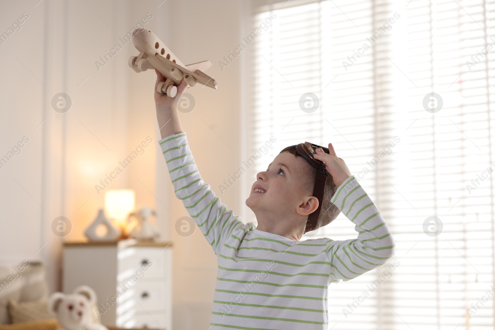 Photo of Happy little boy playing with toy plane at home