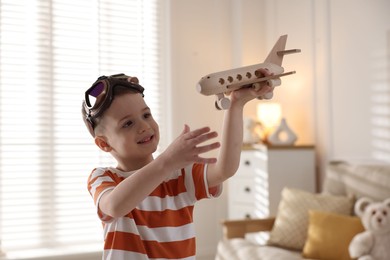 Photo of Happy little boy playing with toy plane at home