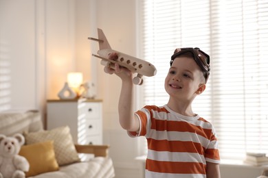 Happy little boy playing with toy plane at home