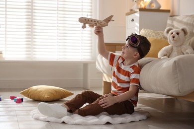 Happy little boy playing with toy plane at home