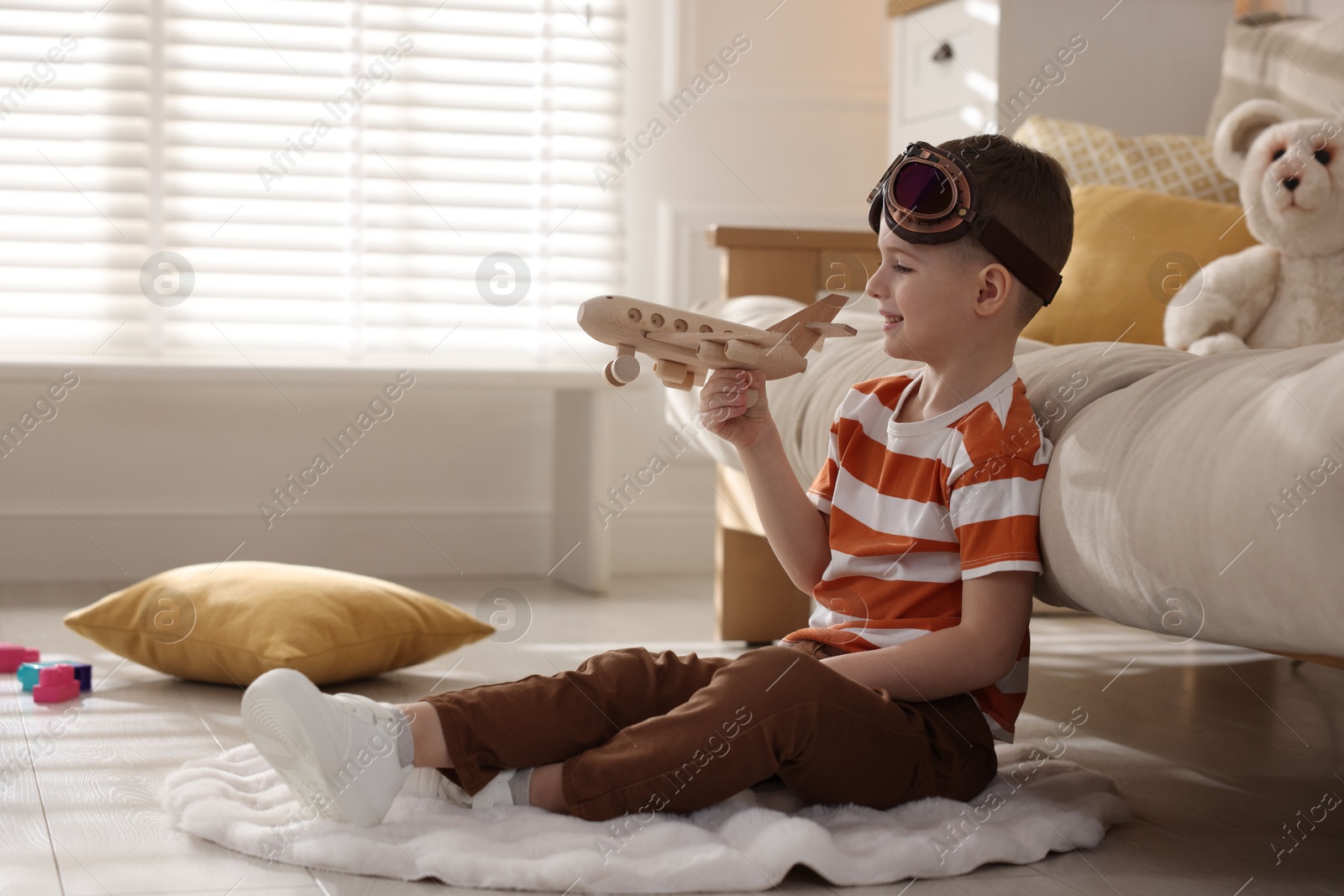 Photo of Happy little boy playing with toy plane at home