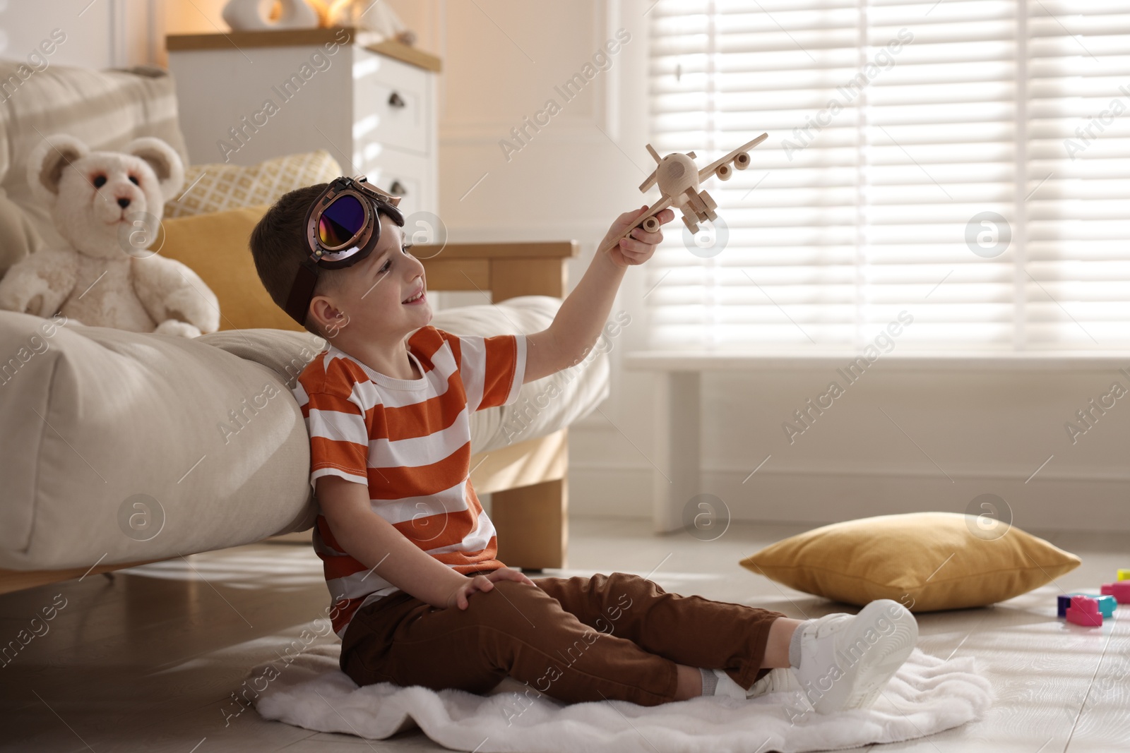 Photo of Happy little boy playing with toy plane at home