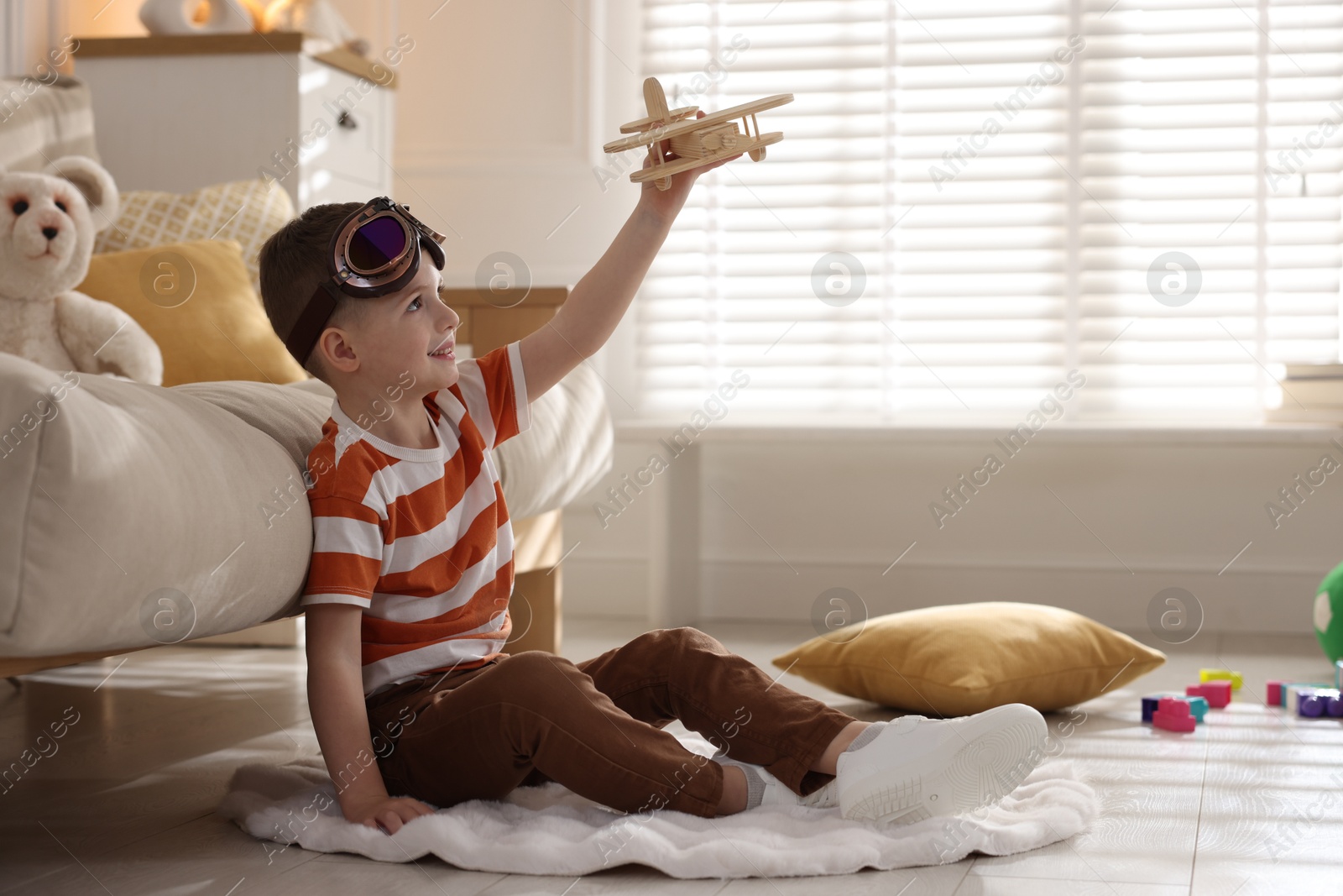 Photo of Happy little boy playing with toy plane at home