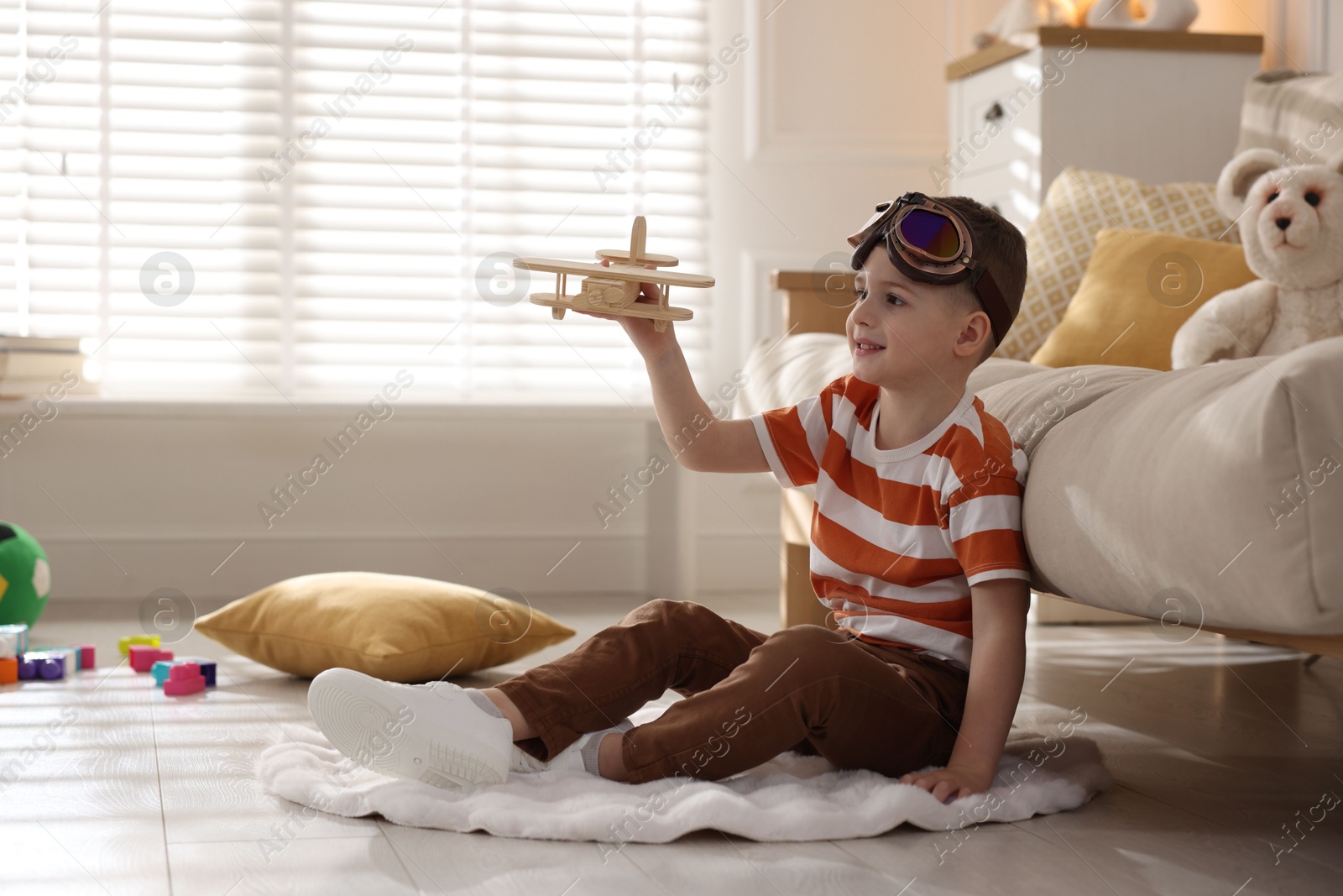 Photo of Happy little boy playing with toy plane at home