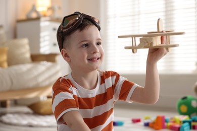 Photo of Happy little boy playing with toy plane at home