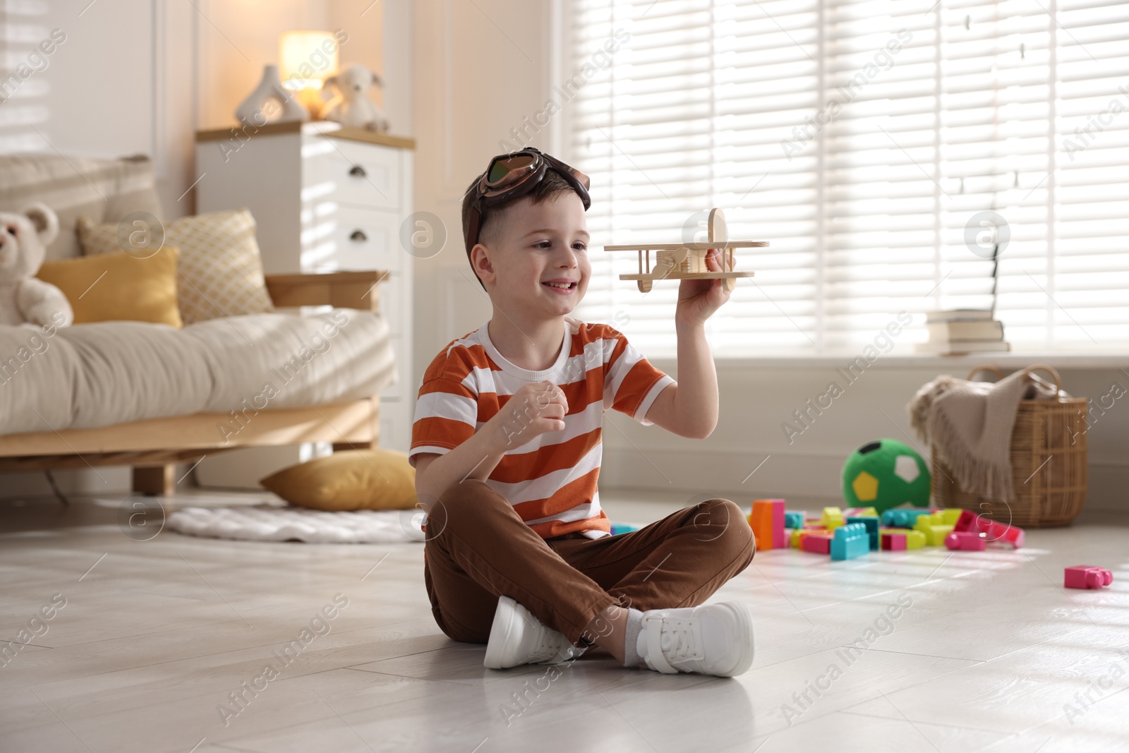 Photo of Happy little boy playing with toy plane at home