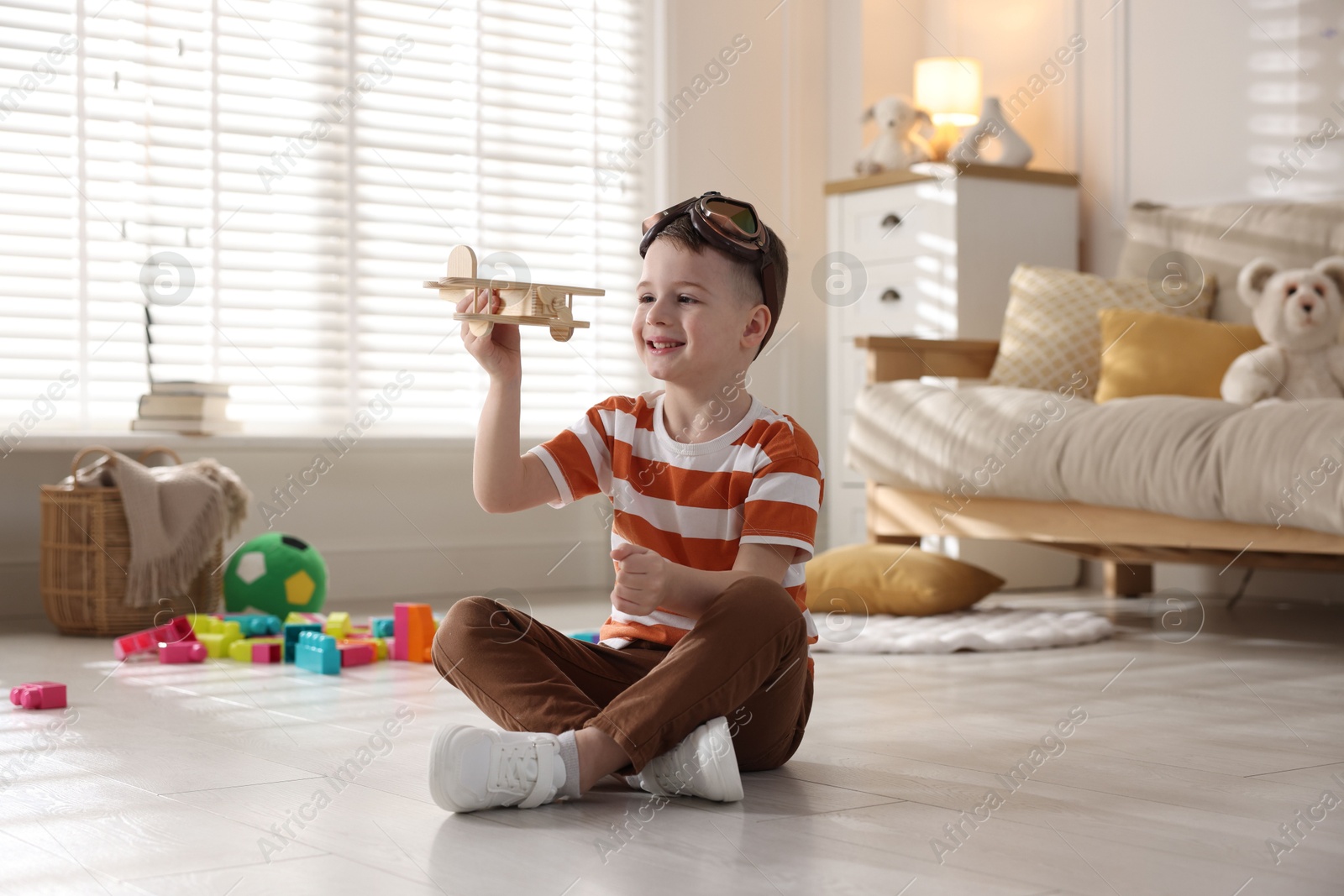 Photo of Happy little boy playing with toy plane at home