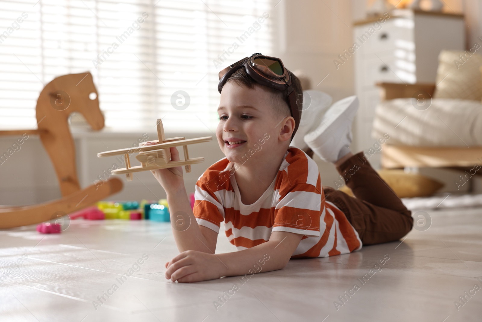 Photo of Happy little boy playing with toy plane at home