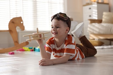 Happy little boy playing with toy plane at home