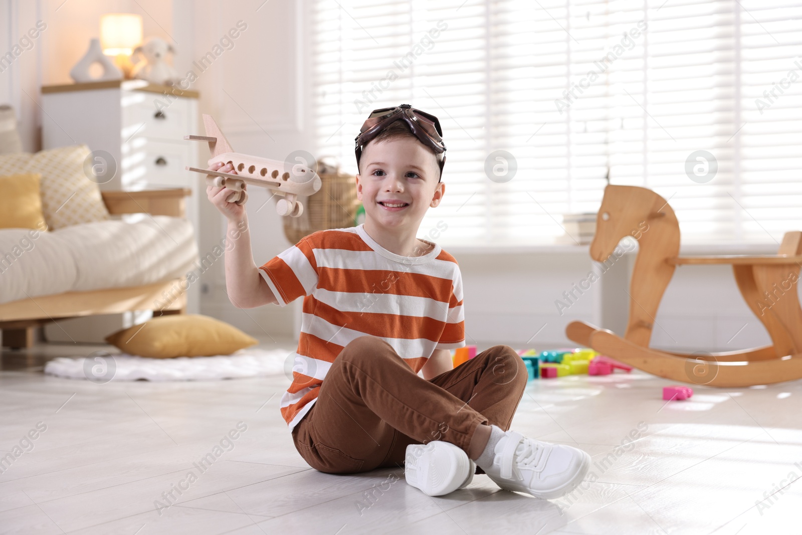 Photo of Happy little boy playing with toy plane at home