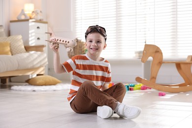 Happy little boy playing with toy plane at home