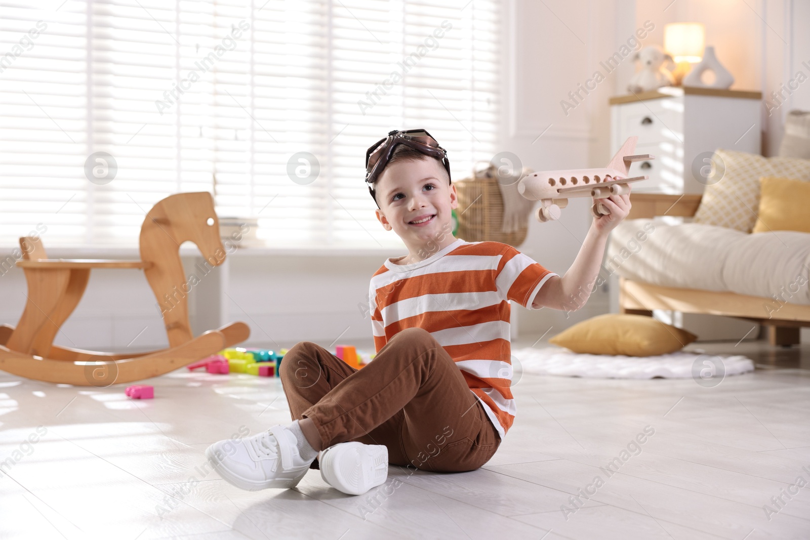 Photo of Happy little boy playing with toy plane at home