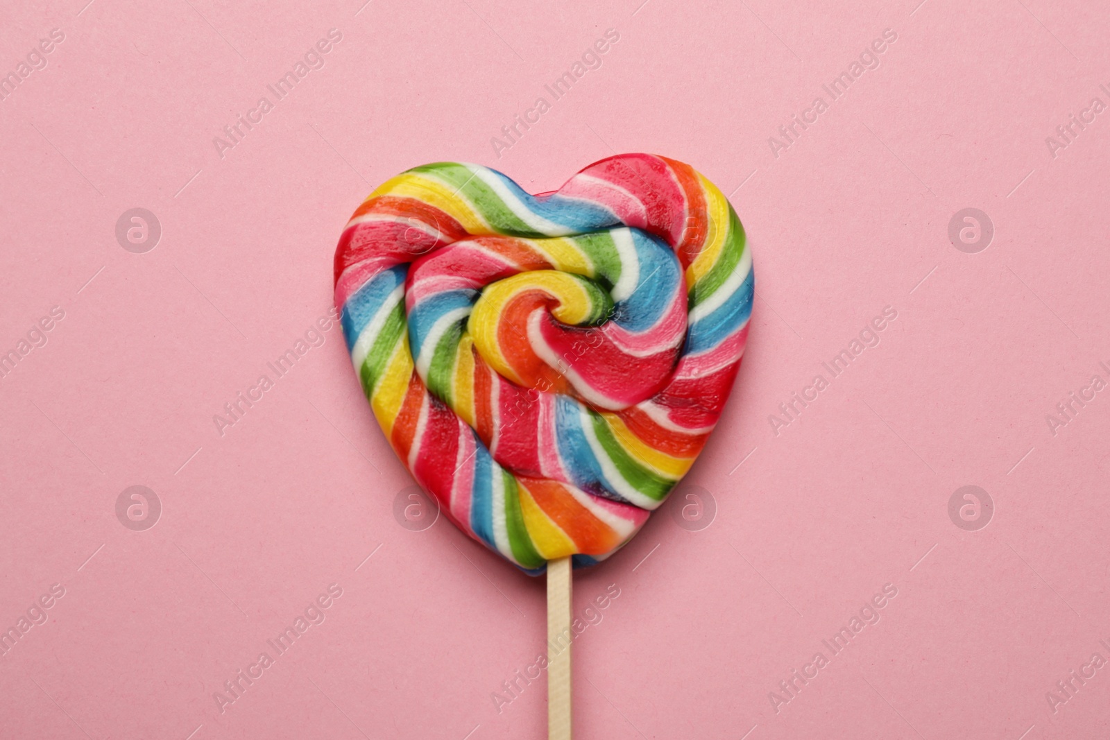 Photo of Tasty heart shaped lollipop on pink background, top view