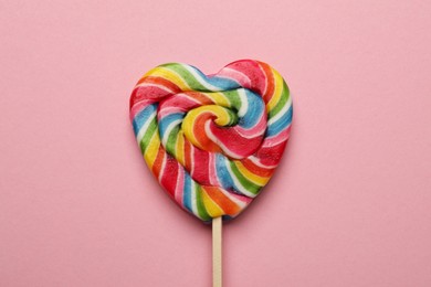 Photo of Tasty heart shaped lollipop on pink background, top view