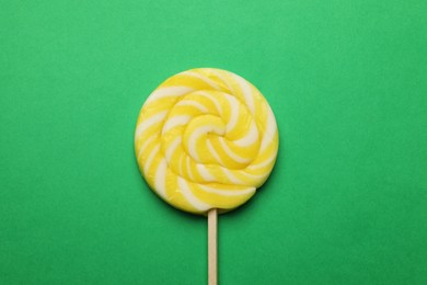 Photo of Tasty striped lollipop on green background, top view