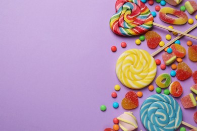 Many different tasty candies and marshmallows on violet background, flat lay. Space for text