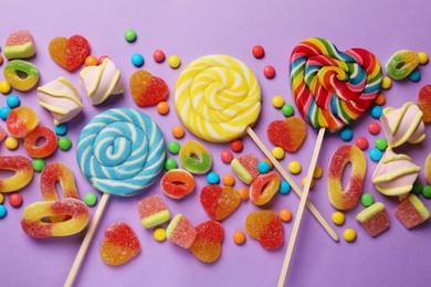 Photo of Many different tasty candies and marshmallows on violet background, flat lay