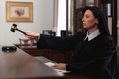 Judge striking gavel at wooden table in courtroom