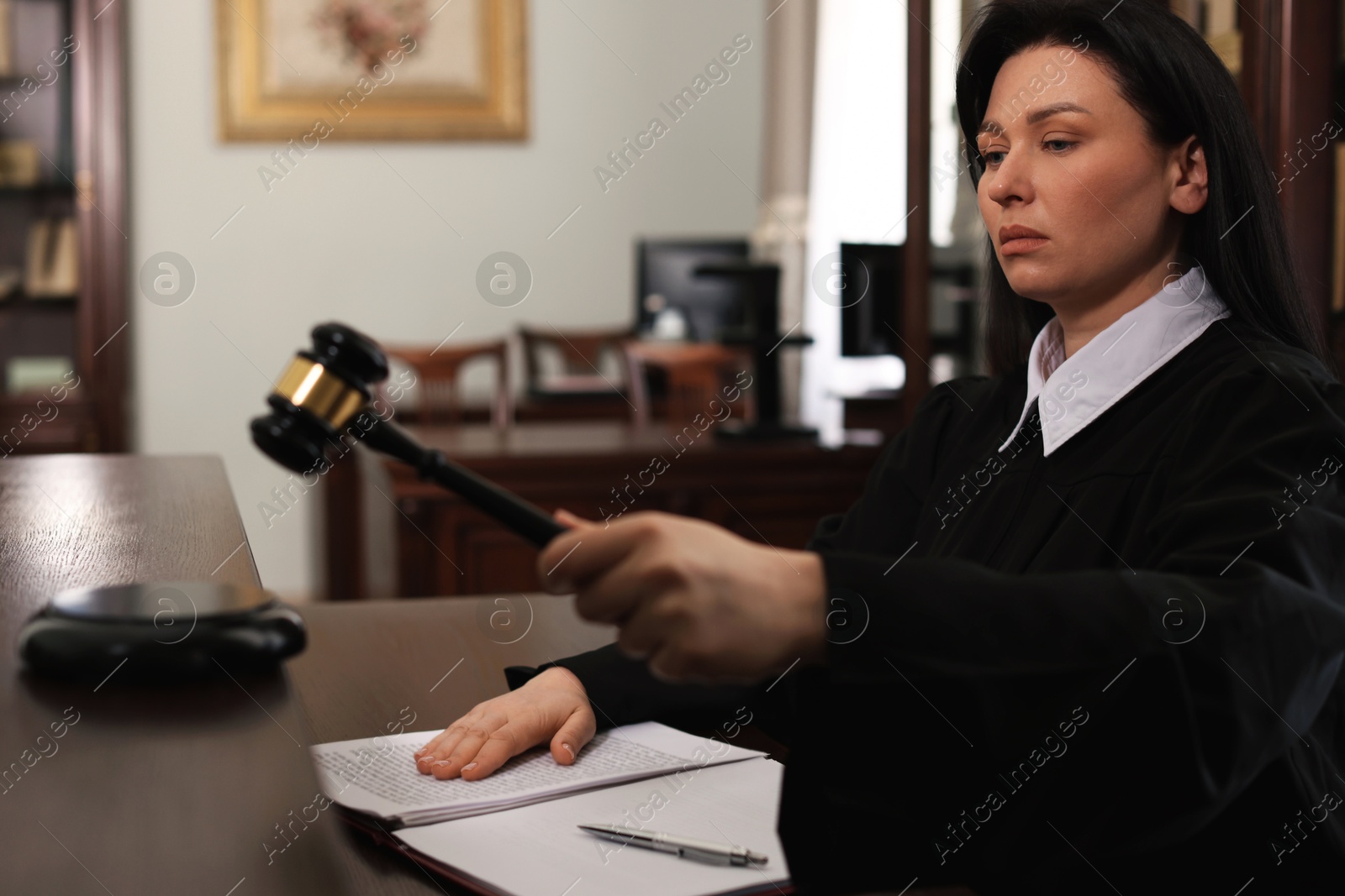 Photo of Judge striking gavel at wooden table in courtroom