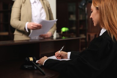 Judge working with documents at table in office, selective focus