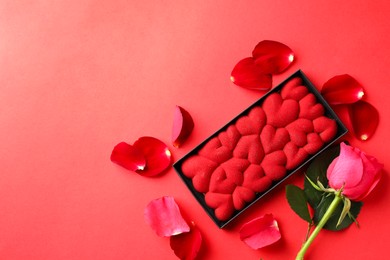 Photo of Chocolate bar decorated with hearts, rose and petals on red background, flat lay. Space for text