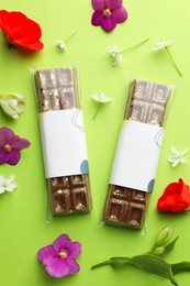 Photo of Delicious Dubai chocolate bars and flowers on green background, flat lay