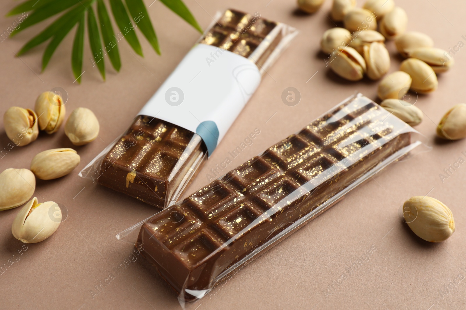 Photo of Delicious Dubai chocolate bars and pistachios on beige background, closeup