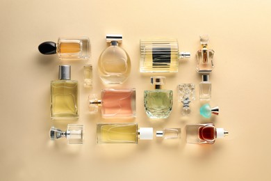 Photo of Bottles of various perfumes on beige background, flat lay