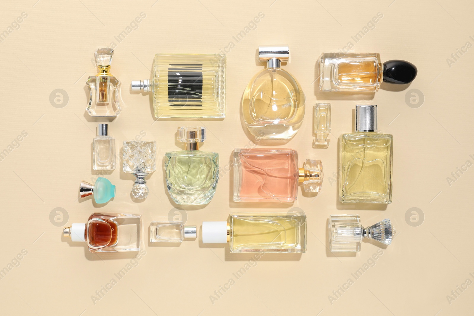 Bottles of various perfumes on beige background, flat lay Photo of Bottles of various perfumes on beige background, flat lay