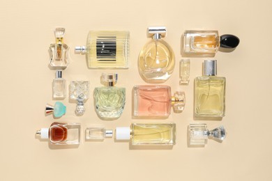 Photo of Bottles of various perfumes on beige background, flat lay