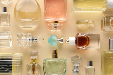 Photo of Bottles of various perfumes on beige background, flat lay