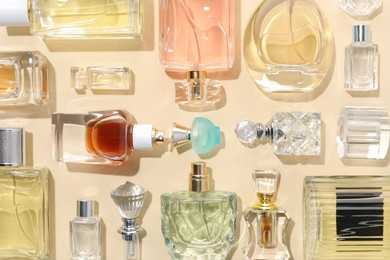 Photo of Bottles of various perfumes on beige background, flat lay