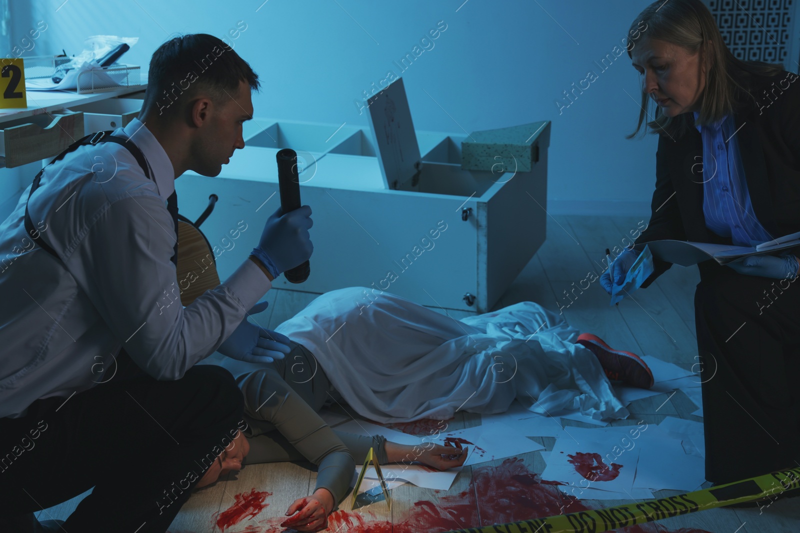 Photo of Forensic experts working at crime scene with dead woman's body indoors