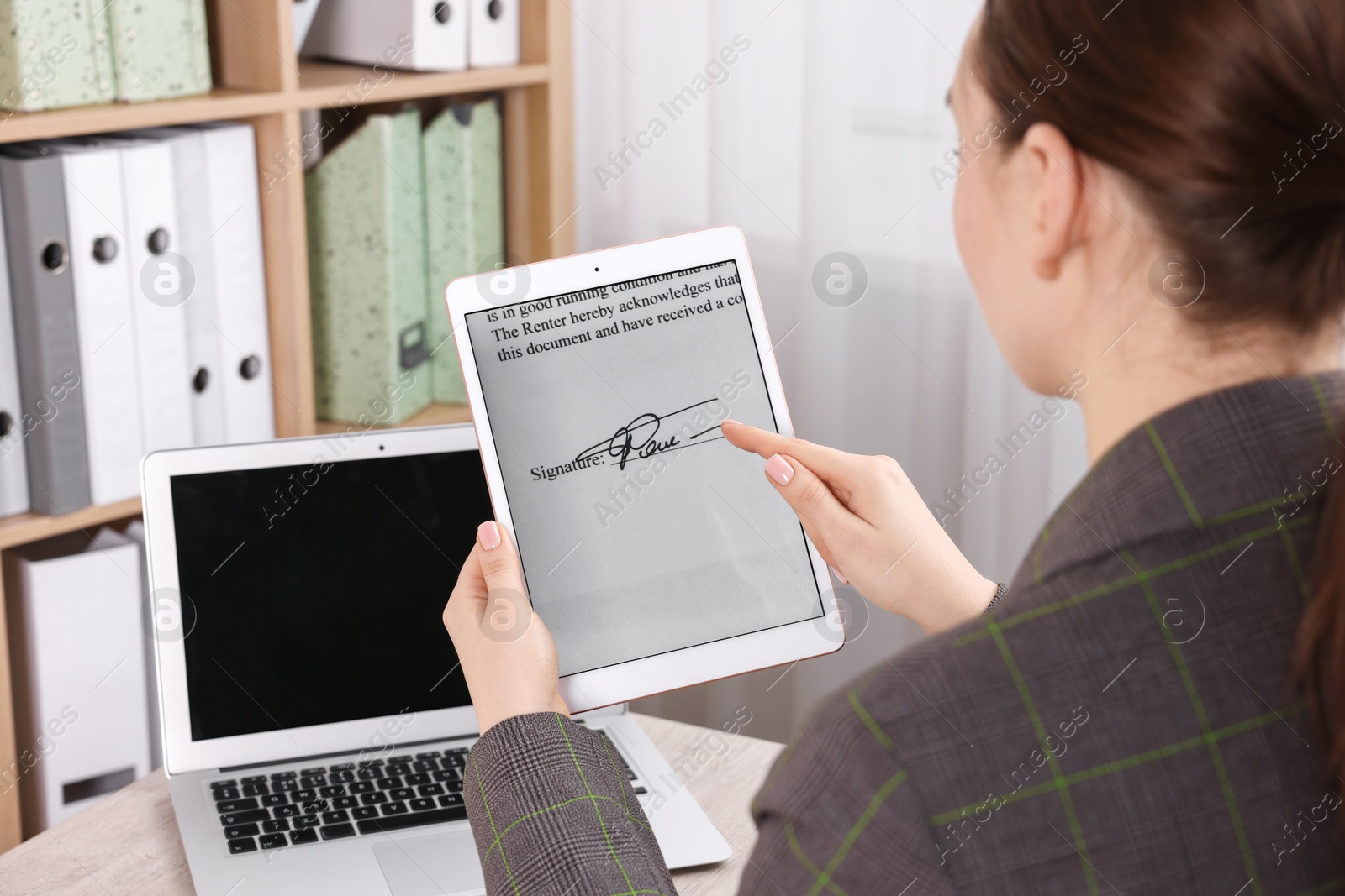 Photo of Electronic signature. Woman using tablet at wooden table indoors, closeup